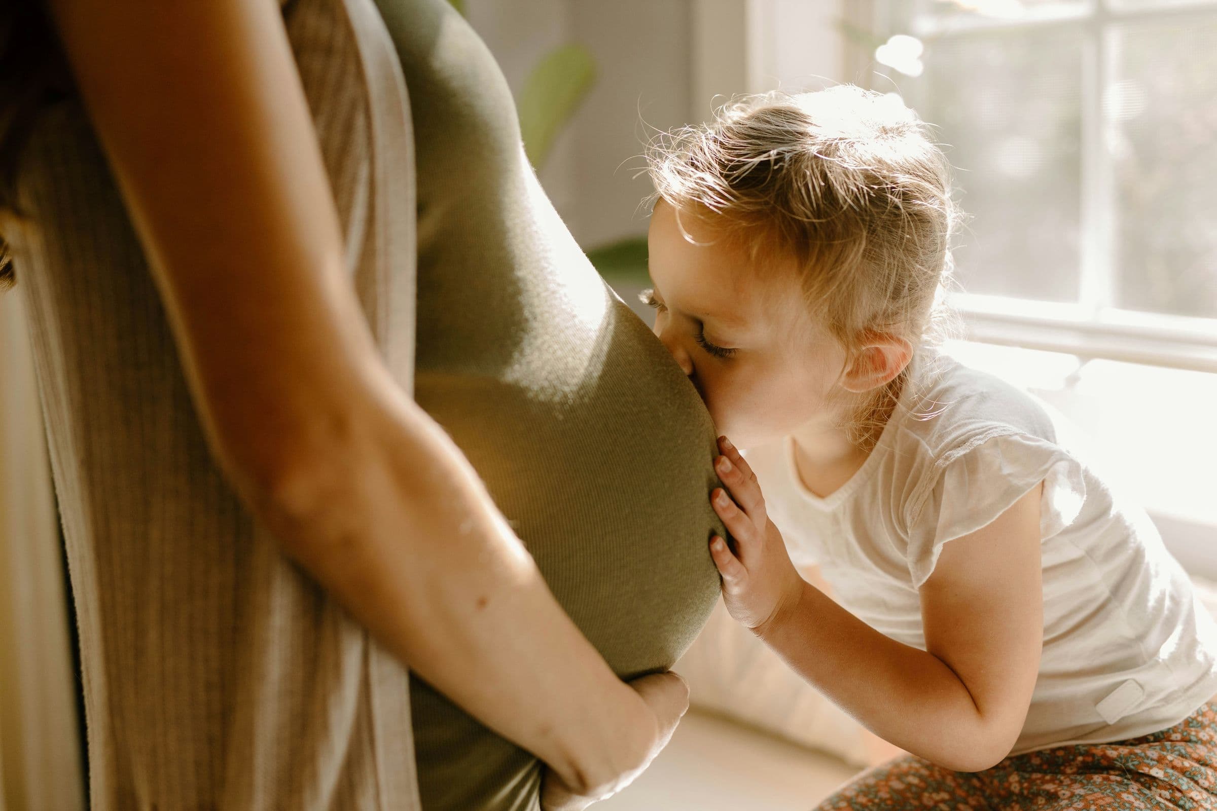 A little boy kissing his mother’s pregnant belly